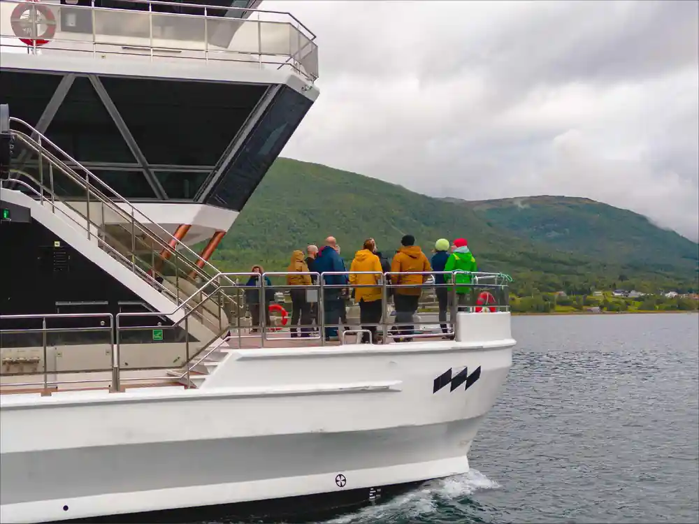 Group of people in colored jackets boarding large passenger vessel