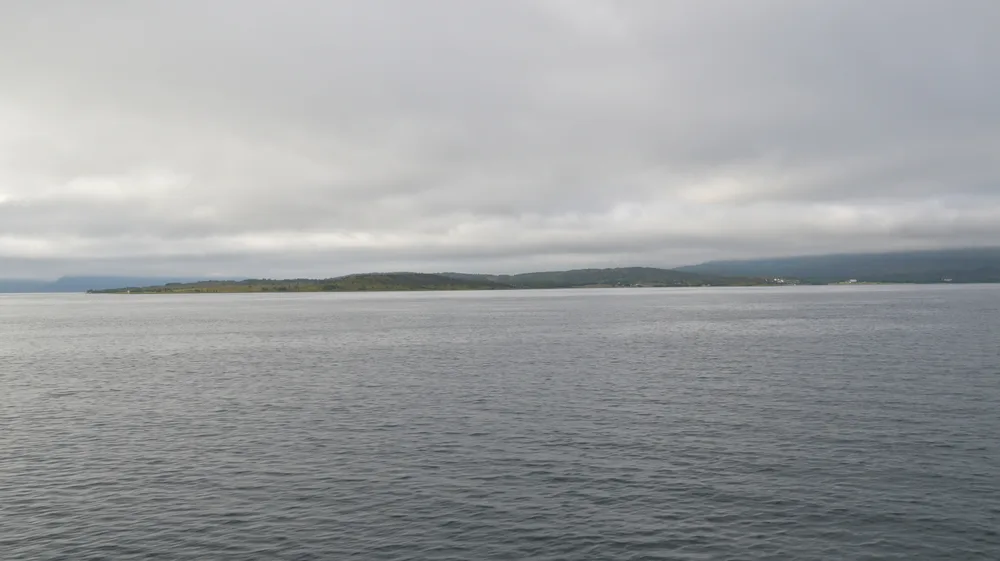 Rystraumen tidal strait seen from the shore with open water and low hills
