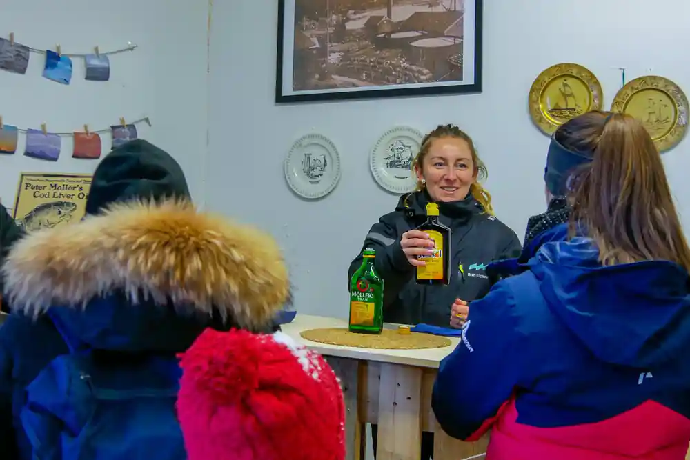 Woman speaking to group indoors, holding beverage bottle