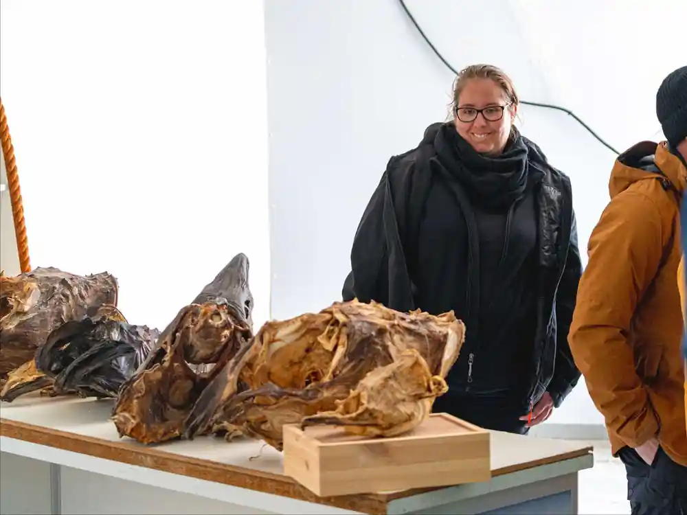 Woman viewing large rocky sculptures in white interior space